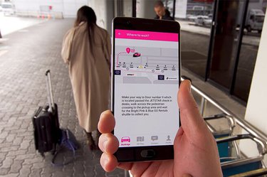 Close up of a person holding a mobile phone with instructions of where to catch the shuttle via the GO Rentals App