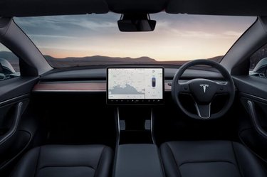 Tesla model 3 interior looking at the road. Wheel, screen and windshield