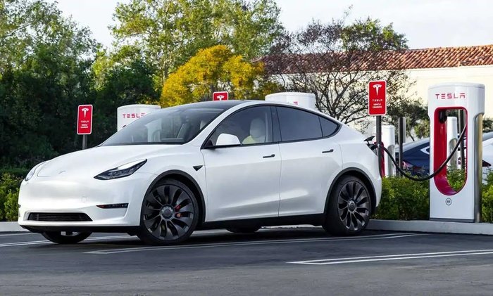 Tesla Model 3 next to a Tesla supercharging station