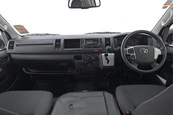 Interior image of a Toyota Hiace 12-seater minibus showing the front dashboard and a view through the windscreen