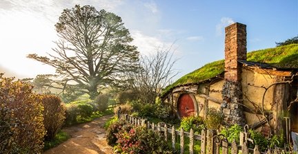 Hobbit house with a round door in a green hill at Hobbiton, New Zealand