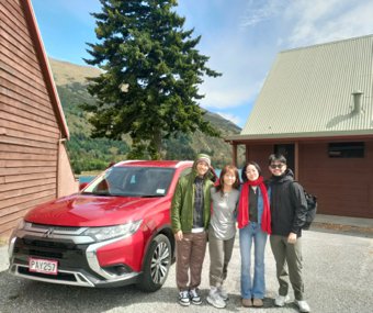 Four friends posing next to a red SUV in a scenic mountain lodge setting